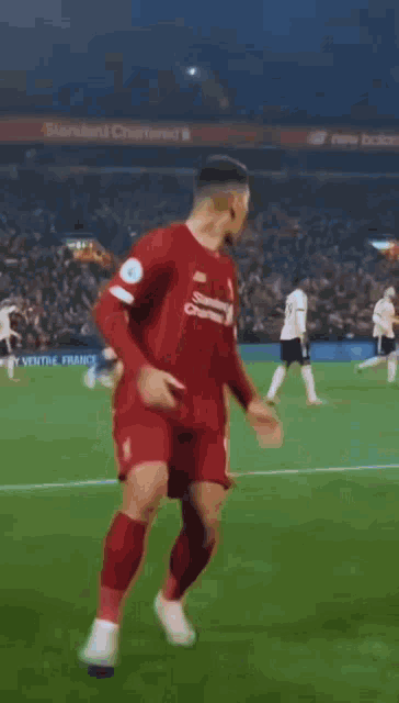 a soccer player wearing a red shirt that says standard chartered on it