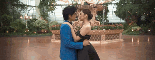 a man in a blue suit and a woman in a black dress are hugging