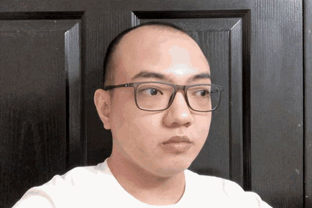 a man wearing glasses and a white shirt is looking at the camera