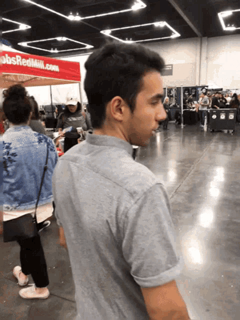 a man in a grey shirt stands in front of a red tent that says jobsredmill.com