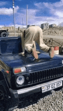 a man is standing on the hood of a car with a license plate that says 37 dz 857