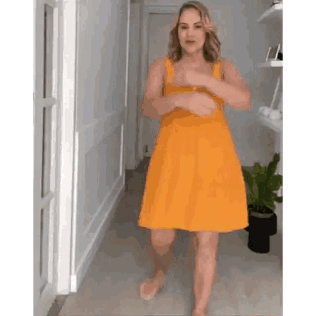 a woman in a yellow dress is dancing in a hallway .