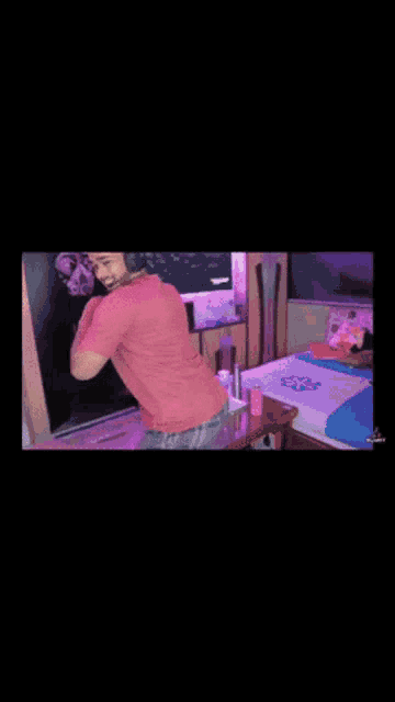 a man in a pink shirt is standing in a bedroom