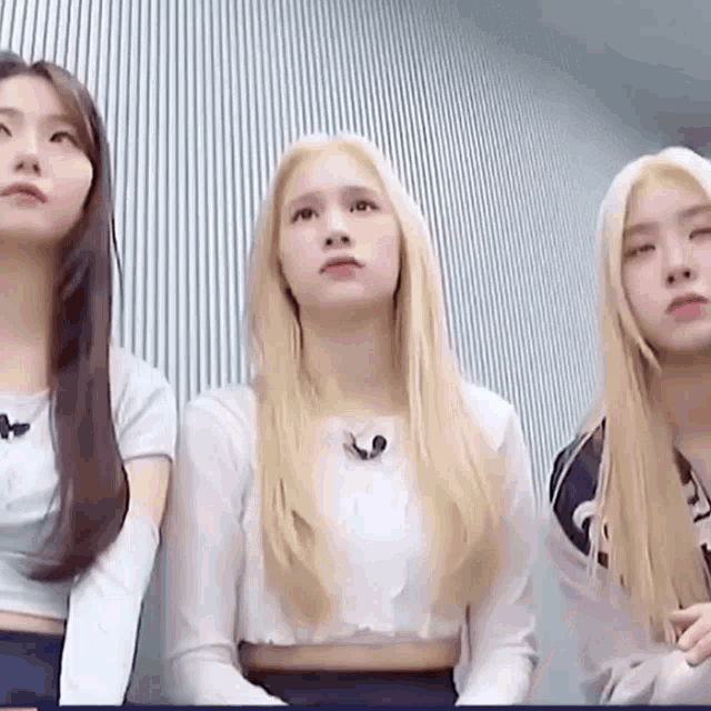 three women are standing next to each other and looking at the camera .