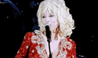 a woman singing into a microphone with a red dress on