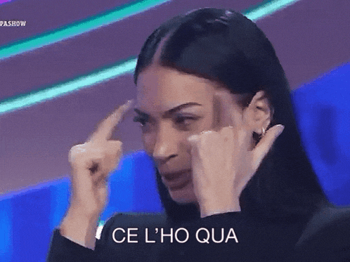 a woman is pointing her finger at her forehead with the words ce l ' ho qua written below her