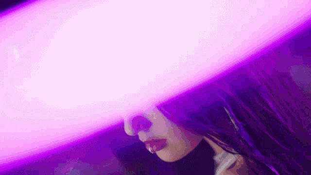 a close up of a woman 's face behind a purple light .