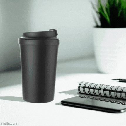 a black coffee cup is sitting on top of a desk next to a notebook and a cell phone .
