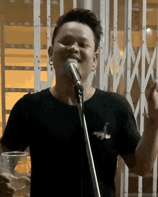 a man is singing into a microphone while holding a plastic cup