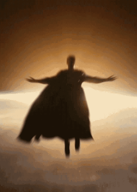a silhouette of a person in a cape flying through the air