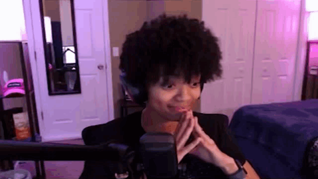 a woman with afro hair is sitting in front of a microphone in a room .