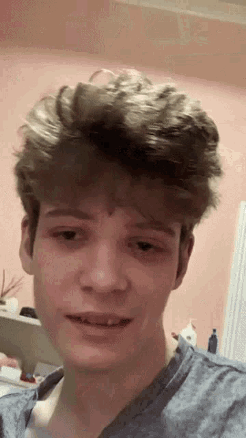 a young man in a blue shirt is looking at the camera .
