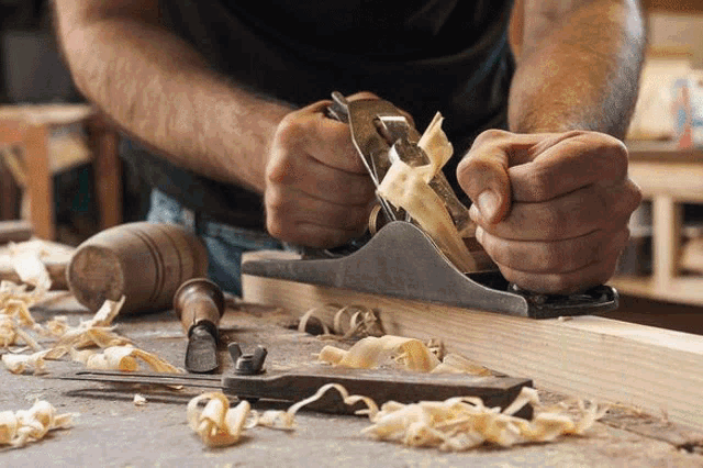 a man is planing a piece of wood with a plane