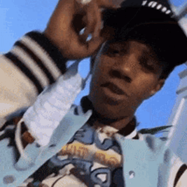 a man wearing a baseball cap and a light blue jacket talks on a cell phone