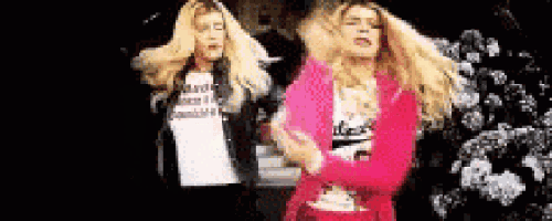 two blonde women are dancing in front of a snowy tree .