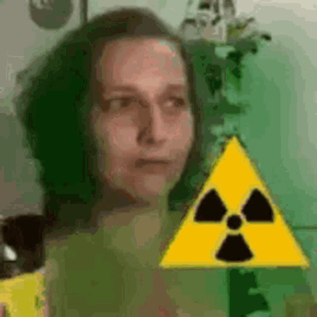 a woman is holding a yellow triangle with a radioactive symbol on it .