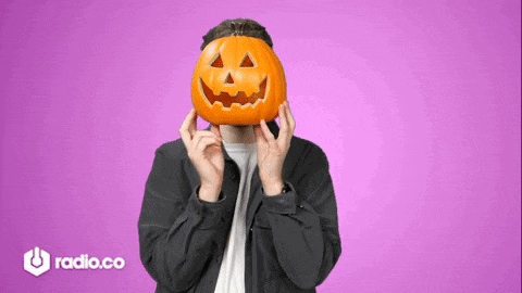 a man is holding a pumpkin in front of his face with radio.co in the background