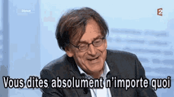 a man in a suit and glasses is laughing and saying `` vous dites absolument n 'importe quoi '' .