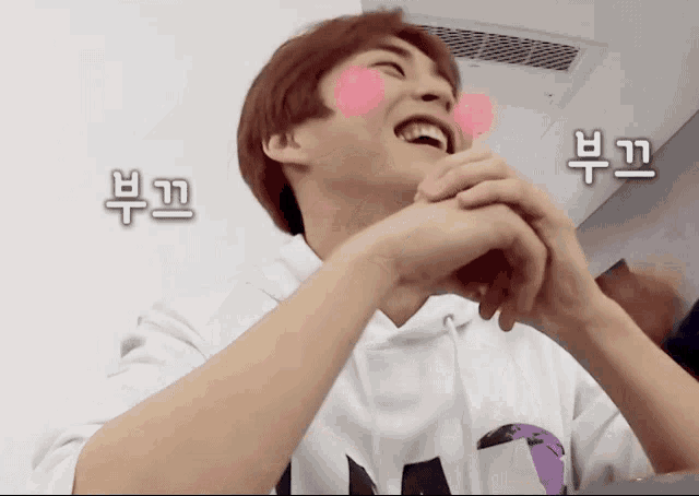 a man with a pink heart on his cheek is smiling in a room with chinese writing on the wall
