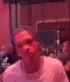 a blurry picture of a man in a white shirt sitting in a room .