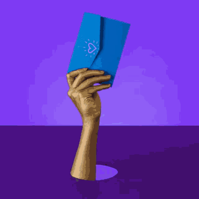 a gold hand is holding an envelope with a heart on it .