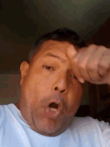 a man is making a funny face while holding his hand to his face