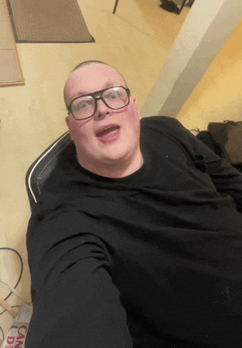 a man wearing glasses and a black shirt takes a picture
