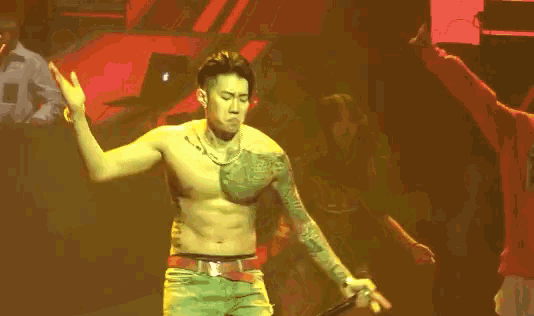 a man without a shirt is dancing on a stage with his arms outstretched .