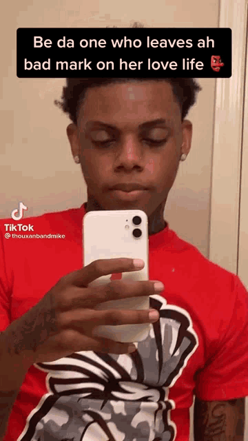 a man in a red shirt is taking a picture of himself with his phone