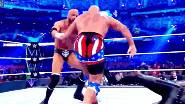 two men are wrestling in a ring and one has an american flag shorts