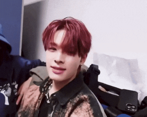 a young man with red hair is sitting in a room with a person holding him .