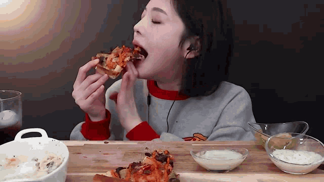 a woman is sitting at a table eating a slice of pizza