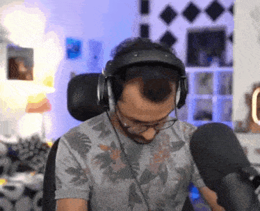 a man wearing headphones and glasses is sitting in a chair in front of a microphone .