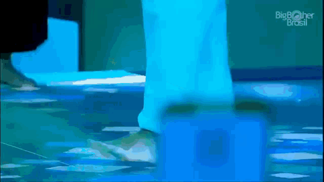 a person 's feet are visible in a blurry photo while standing on a blue surface .