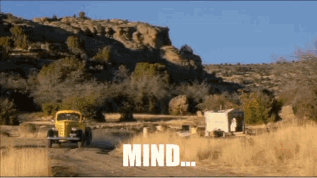 a yellow truck is driving down a dirt road with the words mind written on it