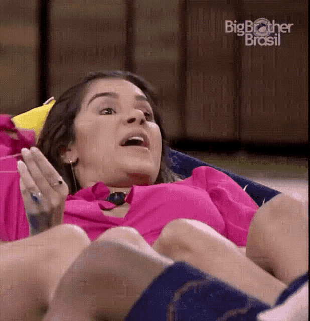 a woman in a pink shirt is laying down with her mouth open and the words big brother brasil on the bottom