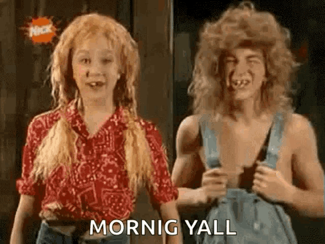 a boy and a girl are standing next to each other . the girl has a wig on and the boy has overalls .