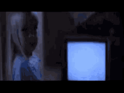 a scary doll is standing in front of a television screen .