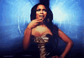 a woman in a black and gold dress holds her hand to her face