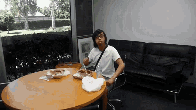 a man is sitting at a table with a plate of food and a bottle of water