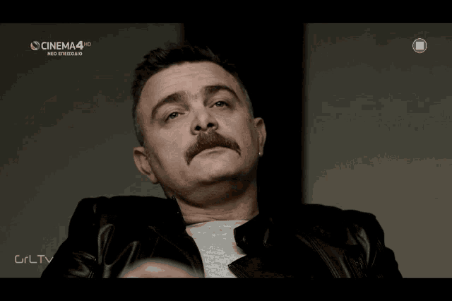 a man with a mustache is sitting in front of a screen that says cinema 4 hd
