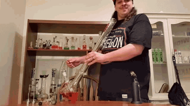 a man wearing a shirt that says helion holds a bong