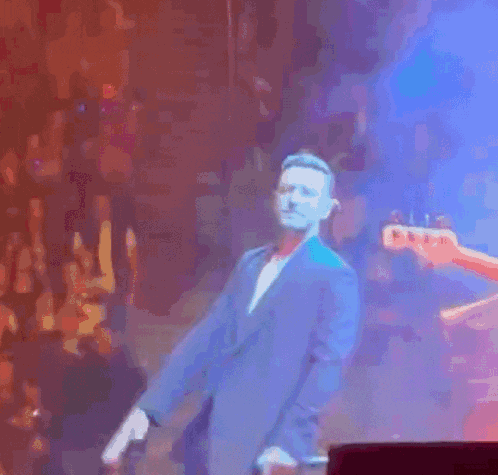 a man in a blue suit and bow tie is dancing on stage