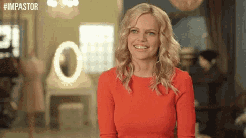a woman in a red dress is smiling in front of a sign that says #impastor