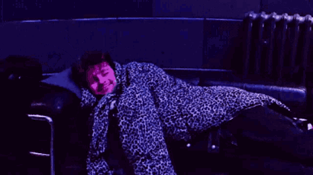 a woman is laying on a couch wrapped in a leopard print robe