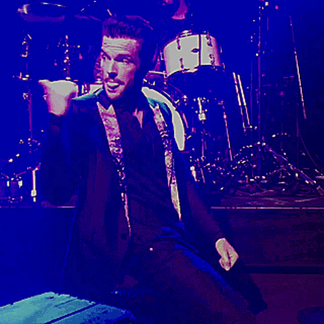 a man in a suit sings into a microphone on a stage