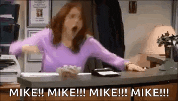 a woman is sitting at a desk with her arms outstretched and screaming .