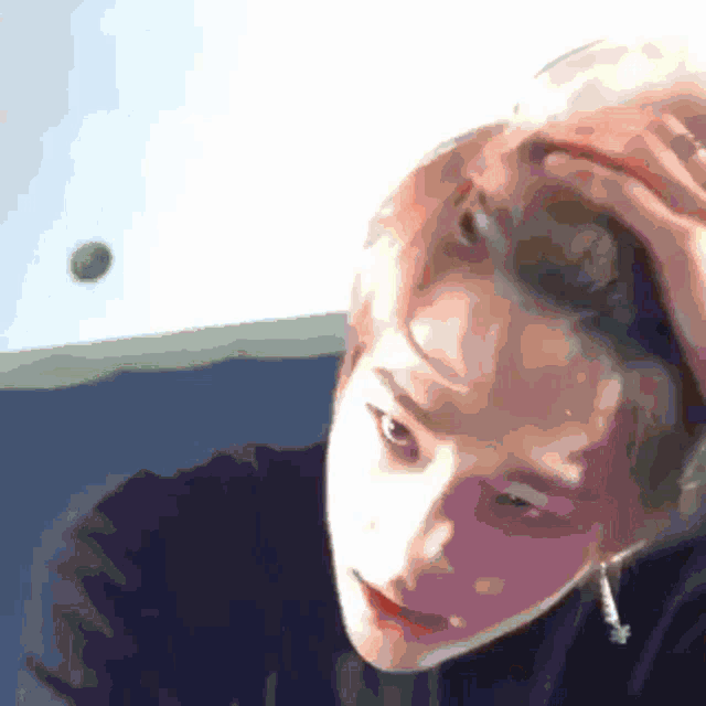 a close up of a person 's face with their hand on their head