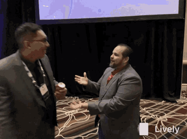 two men are talking in front of a screen that says lively on it