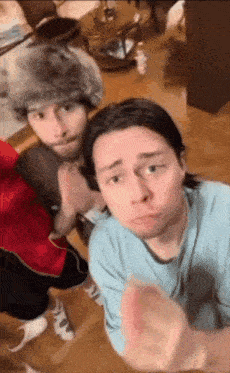 two men are standing next to each other in a living room and one of them is wearing a fur hat